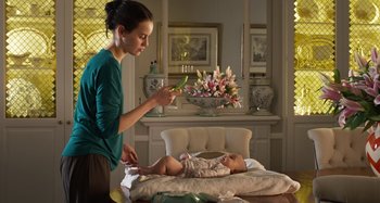 Movie still from “Parallel Mothers” (2021), directed by Pedro Almodóvar – A woman holding a baby in her arms and looking at it; Medium shot, Low angle