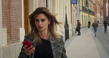Movie still from “Parallel Mothers” (2021), directed by Pedro Almodóvar – A woman walking down the street while holding a cell phone; Close Up shot, Low angle