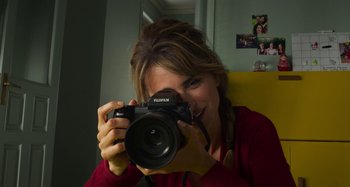 Movie still from “Parallel Mothers” (2021), directed by Pedro Almodóvar – A woman holding a camera up to her face; Close Up shot, Low angle