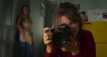 Movie still from “Parallel Mothers” (2021), directed by Pedro Almodóvar – A woman taking a picture of another woman with a camera; Close Up shot, Over the shoulder angle