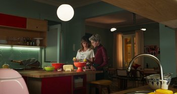 Movie still from “Parallel Mothers” (2021), directed by Pedro Almodóvar – Two women in a kitchen preparing a meal together; Medium shot, Over the shoulder angle