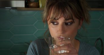 Movie still from “Parallel Mothers” (2021), directed by Pedro Almodóvar – A person drinking a glass of water; Close Up shot, Over the shoulder angle