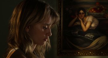 Movie still from “Parallel Mothers” (2021), directed by Pedro Almodóvar – A beautiful young lady sitting in front of a painting; Close Up shot, Over the shoulder angle