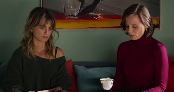 Movie still from “Parallel Mothers” (2021), directed by Pedro Almodóvar – Two women are sitting on a couch and one of them is holding a cup of coffee; Medium shot, Over the shoulder angle