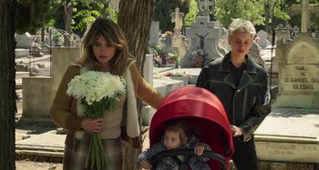 Movie still from “Parallel Mothers” (2021), directed by Pedro Almodóvar – Two women and a child walking in a cemetary; Medium shot, High angle