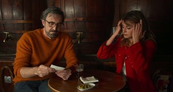 Movie still from “Parallel Mothers” (2021), directed by Pedro Almodóvar – A man and a woman sitting at a table; Medium shot, Over the shoulder angle