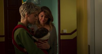 Movie still from “Parallel Mothers” (2021), directed by Pedro Almodóvar – A woman holding a baby in her arms while standing next to a boy; Medium shot, Over the shoulder angle