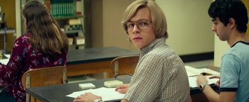 Movie still from “My Friend Dahmer” (2017), directed by Marc Meyers – A person sitting at a table with a book; Medium shot, Over the shoulder angle