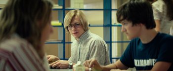 Movie still from “My Friend Dahmer” (2017), directed by Marc Meyers – A man sitting at a table in front of two other people; Medium shot, Over the shoulder angle