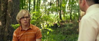 Movie still from “My Friend Dahmer” (2017), directed by Marc Meyers – A woman in a striped shirt standing in a forest; Medium shot, Over the shoulder angle