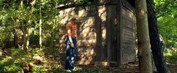 Movie still from “My Friend Dahmer” (2017), directed by Marc Meyers – A man standing in front of an outhouse in the woods; Wide shot, Low angle