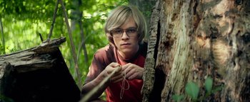 Movie still from “My Friend Dahmer” (2017), directed by Marc Meyers – A man in a red shirt is tying a rope to a tree; Medium shot, Low angle