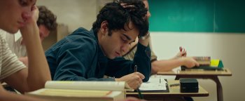 Movie still from “My Friend Dahmer” (2017), directed by Marc Meyers – A man sitting at a desk writing on a piece of paper; Close Up shot, Over the shoulder angle