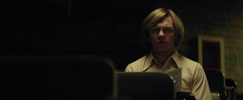 Movie still from “My Friend Dahmer” (2017), directed by Marc Meyers – A man with glasses sitting in front of a computer screen; Medium shot, Low angle