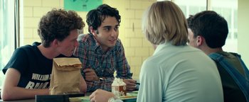 Movie still from “My Friend Dahmer” (2017), directed by Marc Meyers – A man sitting at a table with two other people; Medium shot, Over the shoulder angle