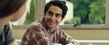 Movie still from “My Friend Dahmer” (2017), directed by Marc Meyers – A young man smiling for the camera while sitting at a table; Close Up shot, Over the shoulder angle