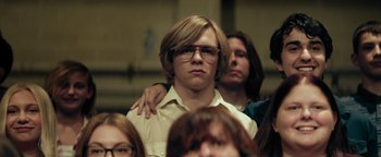 Movie still from “My Friend Dahmer” (2017), directed by Marc Meyers – A man with glasses is standing with his arms around another man; Medium shot, Low angle