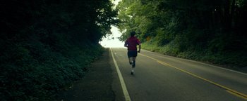 Movie still from “My Friend Dahmer” (2017), directed by Marc Meyers – A man running down the side of a road; Extreme Wide shot, High angle