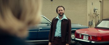 Movie still from “My Friend Dahmer” (2017), directed by Marc Meyers – A man standing in front of a car in a parking lot; Medium shot, Over the shoulder angle