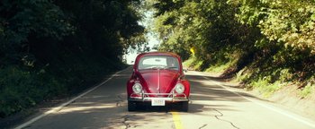 Movie still from “My Friend Dahmer” (2017), directed by Marc Meyers – A red volkswagon beetle car driving down the street; Wide shot, High angle