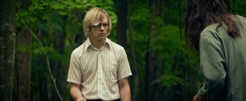 Movie still from “My Friend Dahmer” (2017), directed by Marc Meyers – A man in a striped shirt is standing in the woods; Medium shot, Low angle