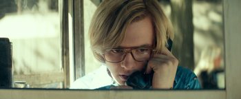 Movie still from “My Friend Dahmer” (2017), directed by Marc Meyers – A man with glasses is talking on a cell phone; Close Up shot, Low angle