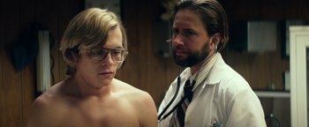 Movie still from “My Friend Dahmer” (2017), directed by Marc Meyers – A man in a white shirt is listening to a woman's ear; Medium shot, Over the shoulder angle