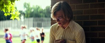 Movie still from “My Friend Dahmer” (2017), directed by Marc Meyers – A young man in a yellow shirt is holding a glass; Medium shot, Low angle