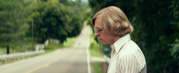 Movie still from “My Friend Dahmer” (2017), directed by Marc Meyers – A man with long blonde hair wearing glasses and a white shirt; Close Up shot, Low angle