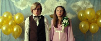 Movie still from “My Friend Dahmer” (2017), directed by Marc Meyers – A man and a woman standing next to each other; Medium shot, Low angle
