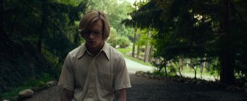 Movie still from “My Friend Dahmer” (2017), directed by Marc Meyers – A young man wearing glasses standing in a wooded area; Medium shot, Low angle