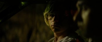 Movie still from “My Friend Dahmer” (2017), directed by Marc Meyers – A man with green hair wearing glasses and a white shirt; Close Up shot, Over the shoulder angle