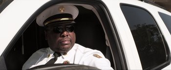 Movie still from “Parker” (2013), directed by Taylor Hackford – A police officer sitting in the driver's seat of a police car; Close Up shot, Low angle
