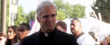 Movie still from “Parker” (2013), directed by Taylor Hackford – A man in a priest's outfit and glasses; Close Up shot, Over the shoulder angle