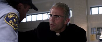 Movie still from “Parker” (2013), directed by Taylor Hackford – A man in a priest's outfit looking at the camera; Close Up shot, Low angle