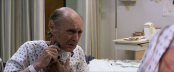 Movie still from “Parker” (2013), directed by Taylor Hackford – An older man is holding a phone in his hand; Close Up shot, Over the shoulder angle