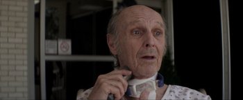 Movie still from “Parker” (2013), directed by Taylor Hackford – An old man is looking at the camera while putting on a neck tie; Close Up shot, Low angle