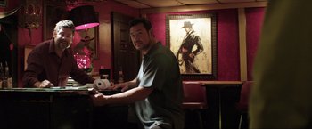 Movie still from “Parker” (2013), directed by Taylor Hackford – A man playing a video game in front of a painting; Medium shot, Low angle