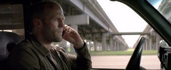 Movie still from “Parker” (2013), directed by Taylor Hackford – A man sitting in a car talking on a cell phone; Close Up shot, Low angle