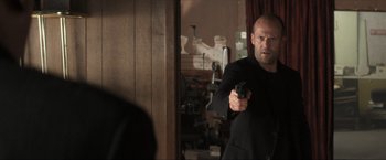 Movie still from “Parker” (2013), directed by Taylor Hackford – A man holding a gun in front of a mirror; Medium shot, Over the shoulder angle