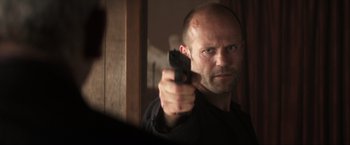 Movie still from “Parker” (2013), directed by Taylor Hackford – A man holding a gun in front of a bathroom mirror; Close Up shot, Low angle