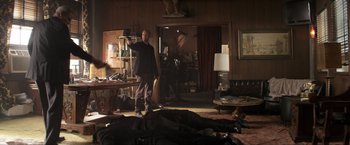 Movie still from “Parker” (2013), directed by Taylor Hackford – A man standing in a living room next to a pile of clothes; Wide shot, Over the shoulder angle