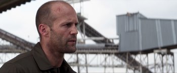 Movie still from “Parker” (2013), directed by Taylor Hackford – A man with a bald head looking to his left; Close Up shot, Low angle