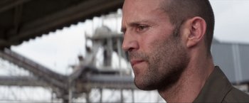 Movie still from “Parker” (2013), directed by Taylor Hackford – A man's face in front of an oil rig; Close Up shot, Low angle