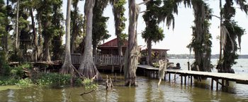 Movie still from “Parker” (2013), directed by Taylor Hackford – A house sitting next to a body of water; Extreme Wide shot, Low angle