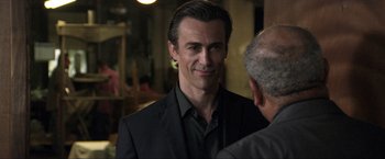 Movie still from “Parker” (2013), directed by Taylor Hackford – A person wearing a suit and smiling; Close Up shot, Over the shoulder angle