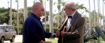 Movie still from “Parker” (2013), directed by Taylor Hackford – Two older men in suits and ties shaking hands outside; Medium shot, Over the shoulder angle