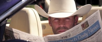 Movie still from “Parker” (2013), directed by Taylor Hackford – A man with a white cowboy hat is reading a newspaper; Close Up shot, Low angle