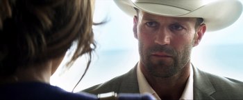Movie still from “Parker” (2013), directed by Taylor Hackford – A person wearing a suit and a white hat; Close Up shot, Over the shoulder angle