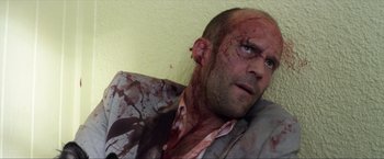 Movie still from “Parker” (2013), directed by Taylor Hackford – A man with a bloody shirt on his face; Close Up shot, Low angle